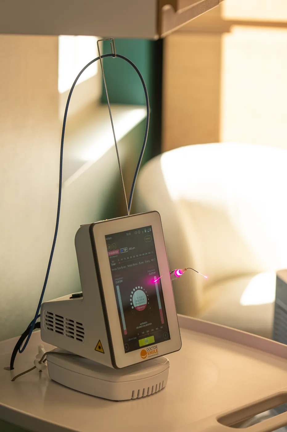 Le laser diode du cabinet, embout allumé, posé sur son support en salle de soins